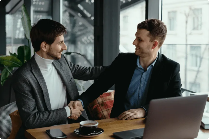 two-businessmen-shaking-hands-while-meeting-lobby-1.png